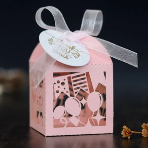 Close-up of pink laser-cut birthday candy box with white ribbon and thank you tag