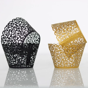 Laser cut cupcake wrappers featuring intricate vine patterns in black and gold finishes