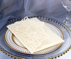 Detail of laser-cut ivory wedding invitation set with floral patterns on glass plate