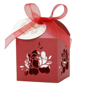 Close-up of laser-cut floral wedding favor box with red ribbon and Thank You tag