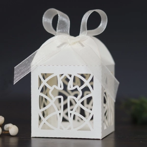 Detailed laser-cut hollow cross design on white gift box with delicate ribbon bow