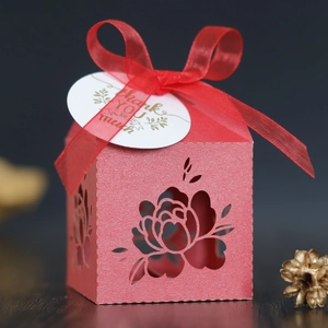 Detail of red laser-cut floral wedding candy box with silk ribbon and thank you tag