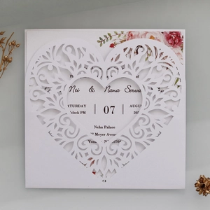 Close-up of pearl white laser cut heart invitation card with intricate vine pattern