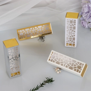 Detailed laser-cut silver and gold candy boxes with geometric cross patterns for weddings