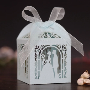 Detail of light blue laser-cut favor box with bride and groom silhouette and ribbon