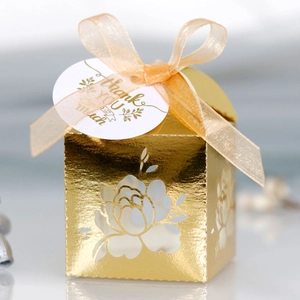 Detailed close-up of golden laser-cut floral wedding candy box with ribbon and thank you tag