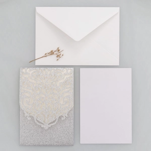 Détail de l'invitation découpée au laser pailletée argentée avec carte interne et enveloppe