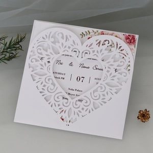 Detailed macro of laser-cut heart vine pattern on elegant white wedding invitation card