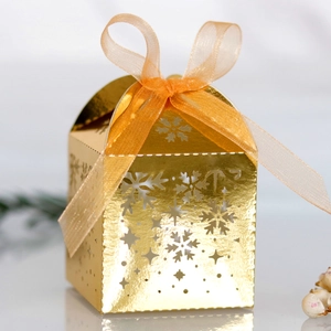 Détail de la boîte cadeau dorée avec flocons découpés au laser et ruban en mousseline