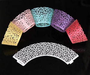 Macro detail of laser-cut vine patterns on colorful paper cupcake wrappers for parties