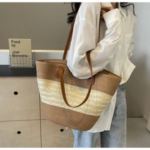 Detail of bohemian straw tote bag with brown leather straps and woven contrast texture
