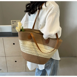 Close-up of large straw tote bag with brown and white stripes and leather handles