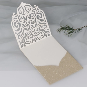 Détail d'invitation de mariage découpée au laser avec dentelle blanche et poche dorée