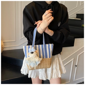 Detail of striped canvas tote with woven straw base and cute teddy bear charm