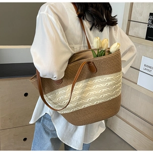 Straw woven tote bag with brown and beige stripes and leather straps shown from behind