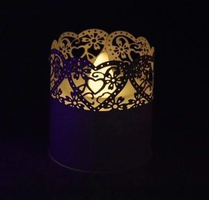 Detailed laser-cut heart and daisy pattern on a white LED candle paper wrap
