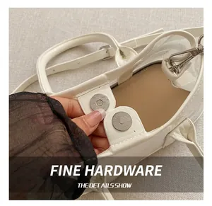 Détail du sac seau en cuir blanc texturé avec un fermoir magnétique argenté élégant
