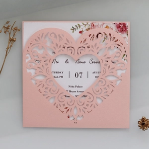 Detail of pink laser-cut heart wedding invitation card with elegant floral inner sheet