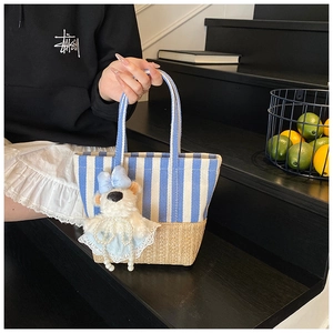 Detail of blue striped tote bag with woven base and cute plush bear charm accessory