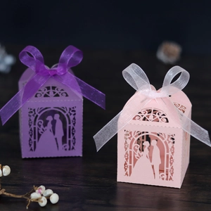 Detail of laser-cut wedding favors boxes with bride and groom silhouette and ribbon