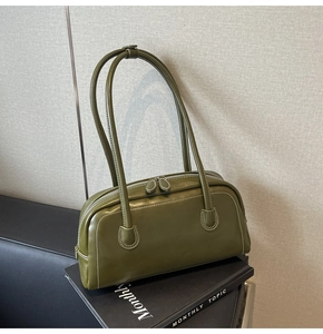 Macro detail of olive green leather shoulder bag featuring white contrast stitching
