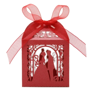 Detail of red laser-cut wedding candy box with bride and groom silhouette and ribbon