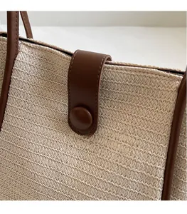 Detail of woven tote bag featuring leather trim, secure snap closure, and fine stitching