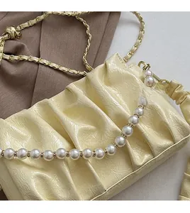Détail du sac nuage plissé jaune clair avec bandoulière en perles et chaîne dorée