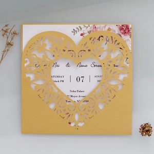 Detail of laser-cut heart wedding invitation with gold shimmer cover and floral insert