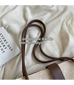 Detail of woven straw tote bag with brown leather handles and a decorative strap