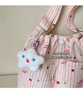 Détail d'un pendentif en peluche étoile blanche avec yeux bleus et mousqueton violet