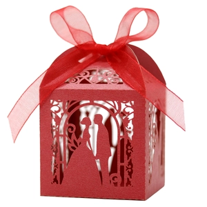 Detail of red laser-cut candy box featuring wedding silhouette and organza ribbon bow