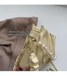 Détail du sac nuage plissé beige avec bandoulière en perles et finitions dorées
