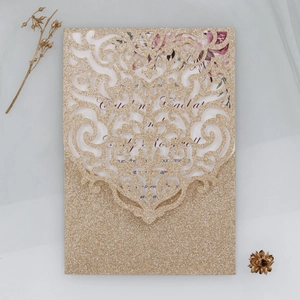 Vue macro de l'invitation découpée au laser champagne avec fleurs et texture pailletée