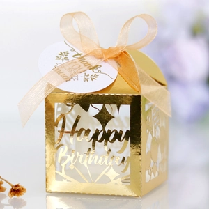 Close-up of golden hollow Happy Birthday gift box with silk ribbon and thank you tag