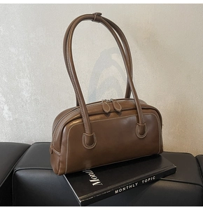 Detail of dark brown retro leather underarm bag with white stitching and dual zippers