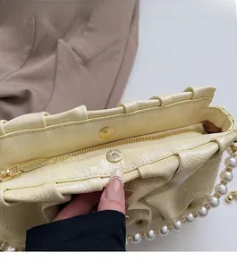 Détail du sac beige plissé avec fermeture magnétique dorée et glissière pratique