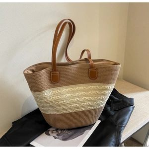 Detail of striped woven tote bag with brown leather handles on a fashion magazine