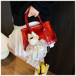Détail du sac seau rouge transparent avec un pendentif en peluche en forme de chien
