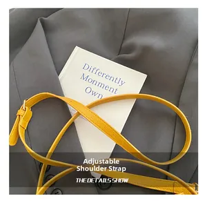 Close-up of yellow leather crossbody strap with adjustable golden buckle and hardware