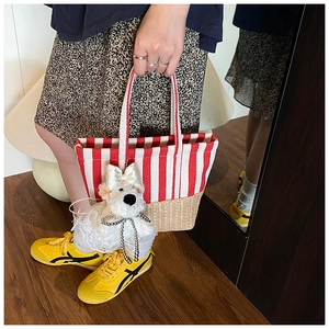 Detail of red striped canvas bucket bag with woven straw base and cute plush bear charm