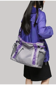 Detail view of large grey travel bag with purple straps and breathable mesh side pocket
