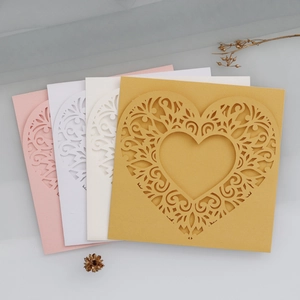 Detail of laser-cut heart pattern on wedding invitations in gold, cream, white and pink