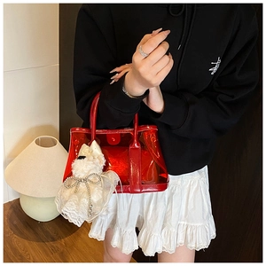 Détail du sac seau en PVC rouge transparent avec un pendentif chien en peluche et dentelle