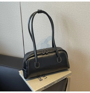 Close-up of black leather underarm bag with white contrast stitching and dual zippers