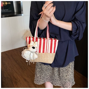 Detail of red striped canvas and straw patchwork handbag with a cute puppy pendant