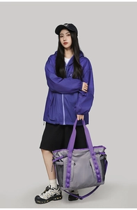 Detail of grey travel bag with purple straps, mesh pocket, and dual-zipper system