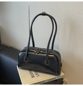 Detail of black Boston bag featuring contrast white stitching and dual metal zippers