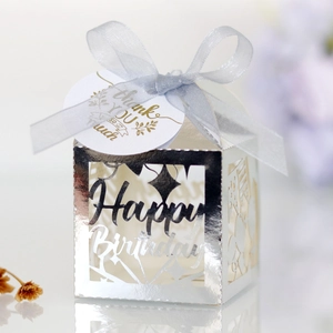 Detail of silver laser-cut Happy Birthday candy box with blue ribbon and thank you tag