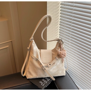 Detail of cream crescent hobo bag with gold buckle and brown plush bear charm
